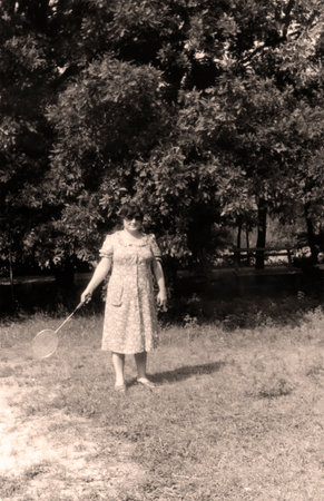 Vintage portrait of beautiful middle-aged woman with badminton racket in hand. Active rest. Retro...