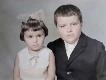 A vintage portrait of a sibling. The girl with the bow looks on in surprise. Retro, 1970s.の写真素材