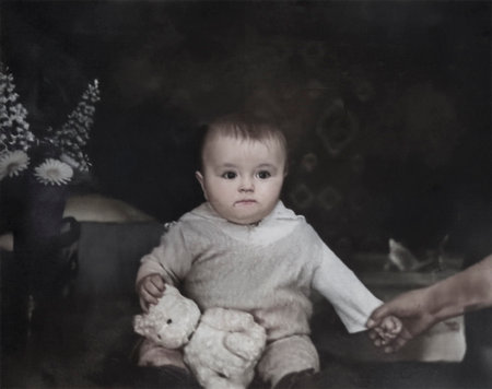 A vintage portrait of a baby girl being held by her mother. The girl is holding a teddy bear. Retro...