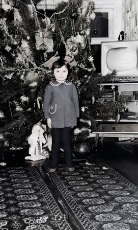 Vintage portrait of a cute little girl by the Christmas tree. Retro photo from 1972.の写真素材