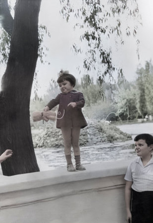 Vintage portrait of little sister and older brother walking in the park. Retro photo from 1972.