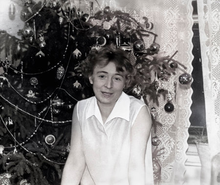 Vintage portrait of a beautiful young smiling woman near a Christmas tree. Retro photo from 1965.の写真素材