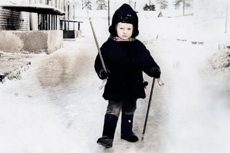 A vintage portrait of a little boy in a fur coat and hat learning to cross-country ski. Retro photo from the 1970s.の写真素材