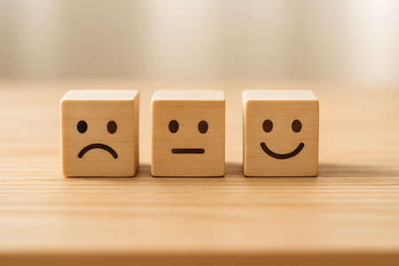Three wooden cubes with simple facial expressions depicting sad, neutral, and happy moodsの素材