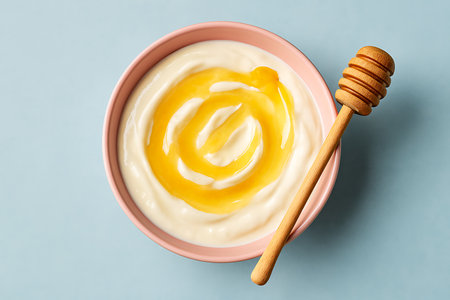 Overhead shot showing creamy yogurt with honey drizzled and dipper, enticing and inviting appeal.の素材