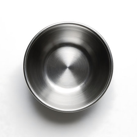 Overhead shot of a polished stainless steel bowl, reflecting light, on a clean white surface.の素材