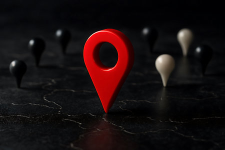 Focused on a vibrant red map pin, standing out against a dark, textured surface with blurred background markers, symbolizing locationの素材