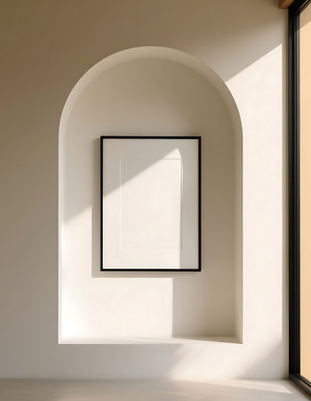 Modern interior features an arched wall niche with a black framed blank picture, illuminated by natural sunlight creating sharp shadowsの素材