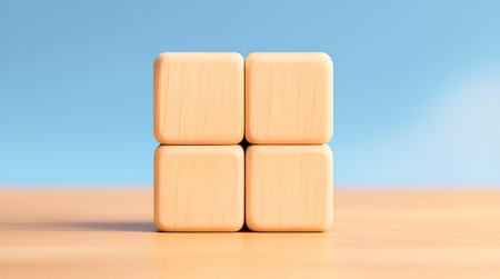 Four light peach colored wooden blocks are neatly stacked in a 2x2 grid, resting on a smooth peach surface against a calm blue backgroundの素材