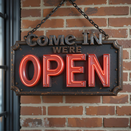 A glowing neon open sign hangs on a rustic brick wall, inviting customers inside to shop now.の素材