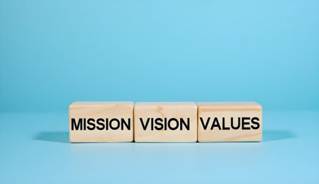 Close-up of three wooden blocks featuring text reading Mission, Vision, and Values against solid blue backgroundの素材