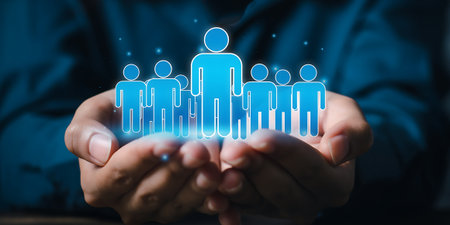 Cupped hands tenderly cradle an illuminated blue group of human silhouettes, symbolizing care and connection within a digital network environmentの素材