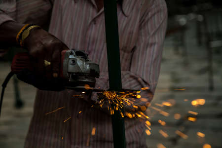 A man is grinding the iron metal to give it final touch