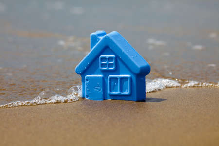 Blue toy plastic house on the sand washes waveの写真素材