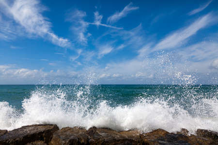 The waves breaking on a stony beach, forming a sprayの写真素材