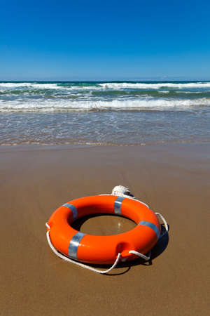 Red lifebuoy lying on the sand on the beachの写真素材
