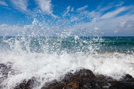 The waves breaking on a stony beach, forming a big sprayの写真素材