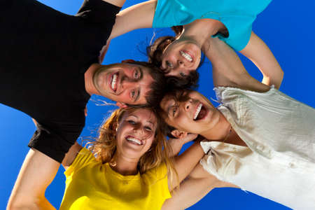 The four friends, embracing, has formed a circle and bent over a photographerの写真素材