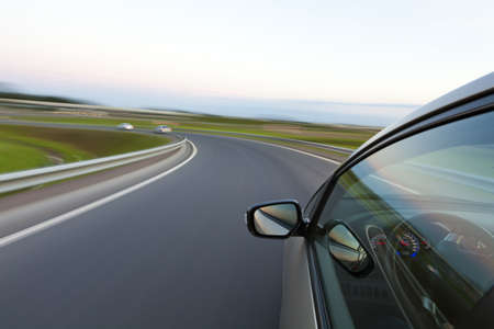 Car goes very fast to turn a country road at nightの写真素材