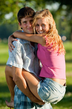 A couple of lovers - a young man holding a girl on his hands in the park, and both were smilingの写真素材