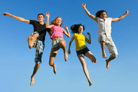 Four young boys and girls jumping on a background of blue skyの写真素材