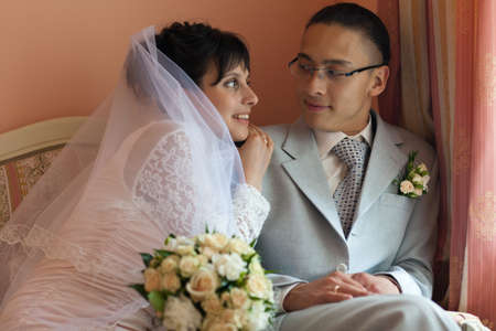 Sitting on the couch in her boudoir, the bride groom gently touched his shoulder and smilesの写真素材