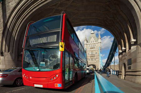 The famous Tower Bridge in London, UK. Double-decker bus passes under the arch of the tower. Sunny day. Photograph taken with the tilt-shift lens, vertical lines of architecture preservedの写真素材