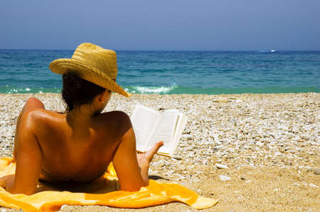 Pretty girl reading novel at beautiful beachの写真素材