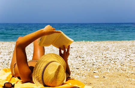 Pretty girl reading novel at beautiful beachの写真素材