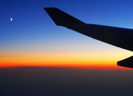 Flying High - sunset view of plane wing and moonの写真素材