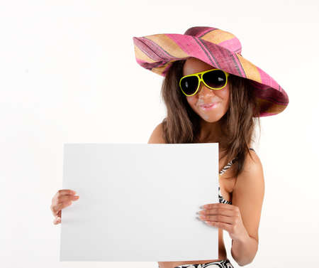 Beautiful young brunette woman in cowboy hat and yellow sunglasses displaying billboard for copy spaceの写真素材