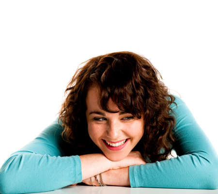 Teenage smiling brunette girl, lying on a desk with head on handsの写真素材