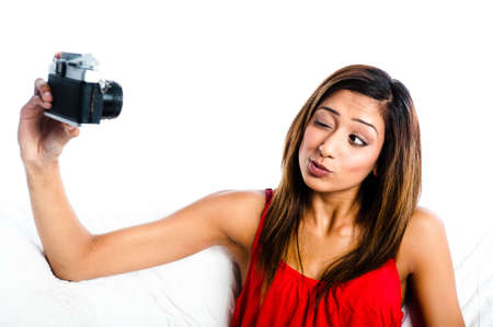Young Asian Indian girl with old camera, taking photos of herself, winking to her cameraの写真素材