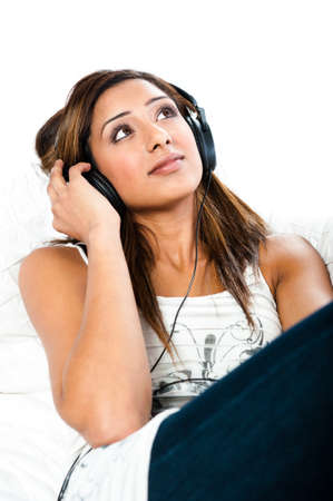 Beautiful asian indian teenage girl, listening to music with her eyes open sittingの写真素材