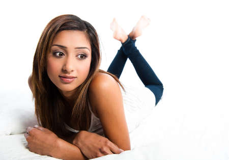 Beautiful asian indian teenage girl laying down, in thought with arms foldedの写真素材