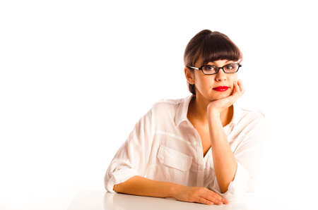 Professional young woman with glasses and red lipstick, sitting at a desk with head resting on faceの写真素材