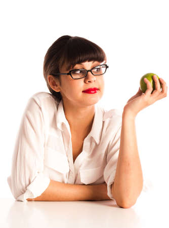 Professional young woman sitting at a desk with an apple in hand wearing glasses and red lips. glancing at green appleの写真素材