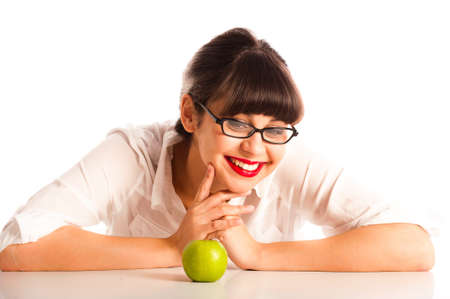 Professional young woman resting on a desk with an apple and glasses. Smiling at the appleの写真素材