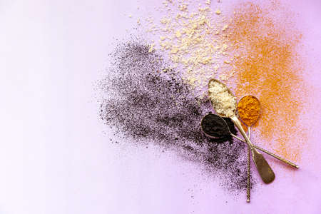 Activated carbon, cocos and curcuma explosion from spoons on a pink background