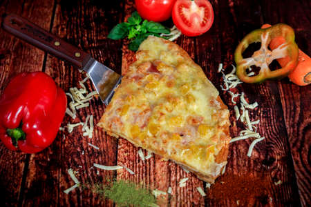 Top view of sweet Hawaiian homemade pizza slice with fresh veggies decor on wooden backgroundの写真素材