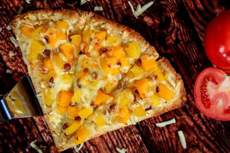 Up close and top view of special sweet pizza slice with mango and pineapple topped with a special...