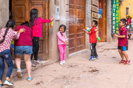Pisac, Peru - 02.23.2020: Peruvian kids playing with foam toy-guns on the streets of Pisacのeditorial素材