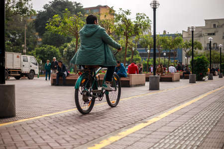 Lima, Peru - 12.02.2019: Peruvian person wearing a green jaket riding a bicycle on a bicycle trackの写真素材
