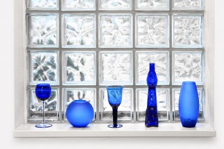 Blue vases and glassed in front of transparent glass tile windowの写真素材