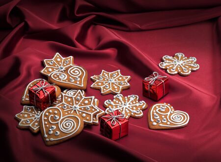 Decorated Christmas gingerbread cookies on red silky textile backgroundの写真素材