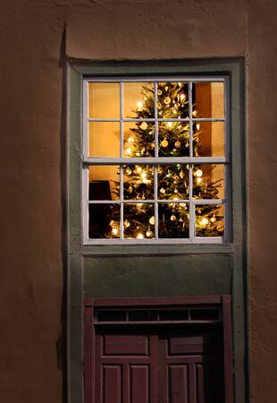 Christmas tree seen from outside of an old house windowの写真素材