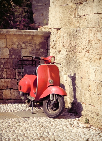 Red vintage scooter on old stone paved streetの写真素材