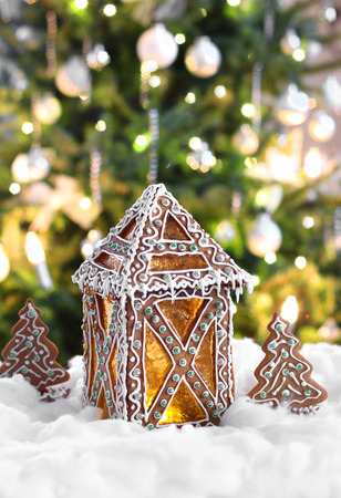 Gingerbread lantern in front of illuminated Christmas treeの写真素材