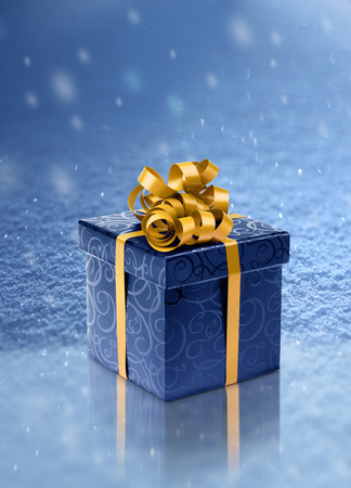 Blue present box on ice in realistic snowfall backgroundの写真素材