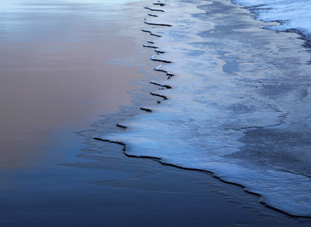 Lake water partially covered with ice, seasonal climateの写真素材